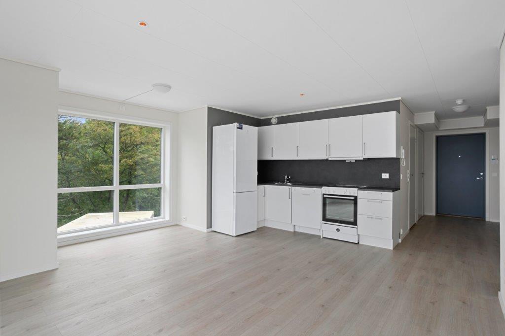 Ope kjøkken med stor plass til matbord. Lyse fargar og stort vindauge. Foto.