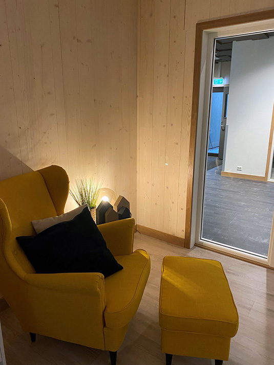 Personalbase med koselig belysning og lenestol. Foto.