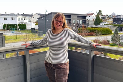 Ingrid står på balkong med nabolag i bakgrunnen. Foto.