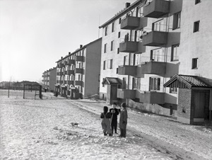 Barn leker ute i et boligområde med blokker på 1950-tallet. Foto.
